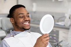 Man smiling at reflection in handheld mirror