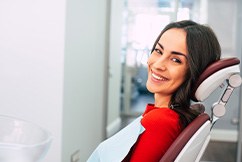Woman in red shirt smiling in treatment chair