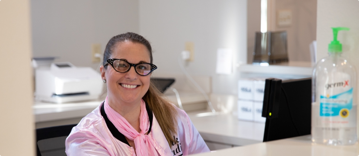 Smiling Slidell dental team member sitting at desk