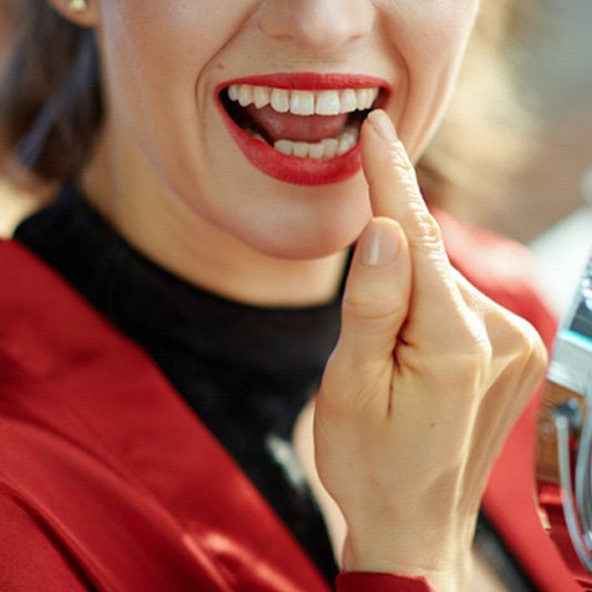 Woman pointing to her tooth after getting direct bonding in Slidell