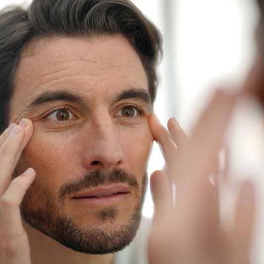 Man looking at his facial wrinkles in a mirror