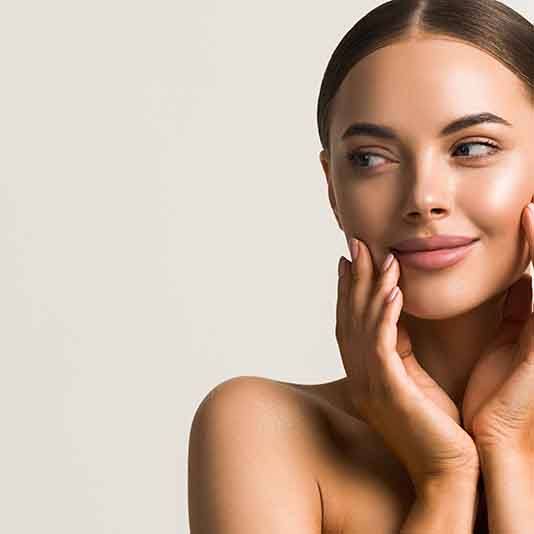 Smiling woman with smooth skin touching her face