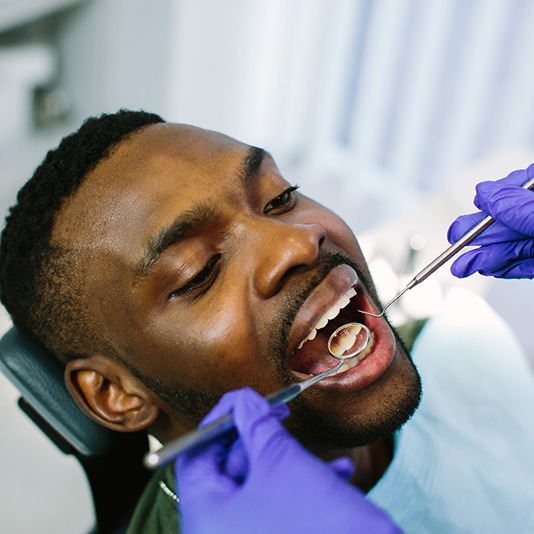 Dentist using tools to examine patient's teeth