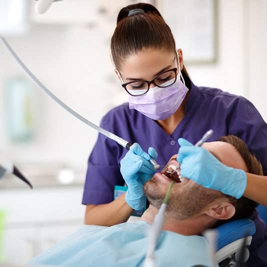 Dental hygienist using tools to clean patient's teeth