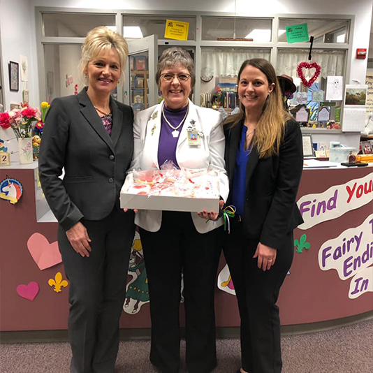 Three women holding a cake in Slidell dental office