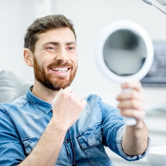 Dental patient admiring his smile in mirror