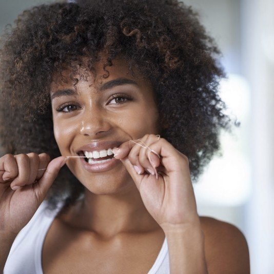 Woman smiling while flossing her teeth