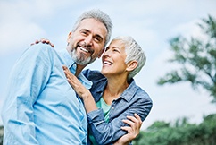 Senior couple smiling while hugging outside