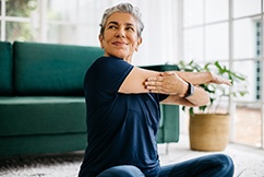 Senior woman smiling while stretching at home