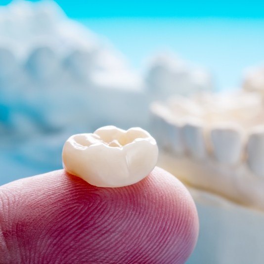 Restorative dentist holding a dental crown on their finger