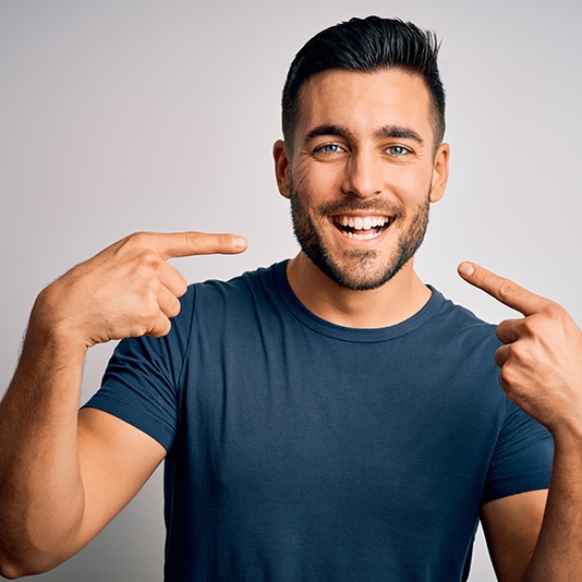 a man smiling and pointing to his teeth