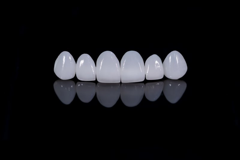 A close-up of straight porcelain veneers against a black background