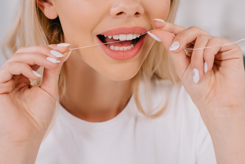A woman flossing with dental implants