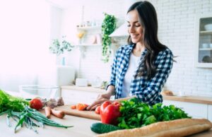 smiling woman cutting up raw vegetables